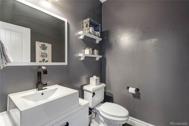 bathroom with toilet, baseboards, and vanity