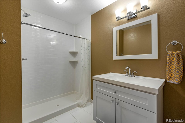 full bathroom with a textured wall, curtained shower, tile patterned flooring, and vanity