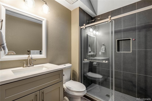 full bathroom with a textured wall, vanity, toilet, a shower stall, and visible vents