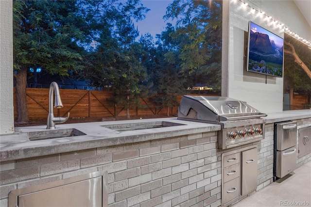 view of patio / terrace with fence, exterior kitchen, area for grilling, a sink, and a fire pit