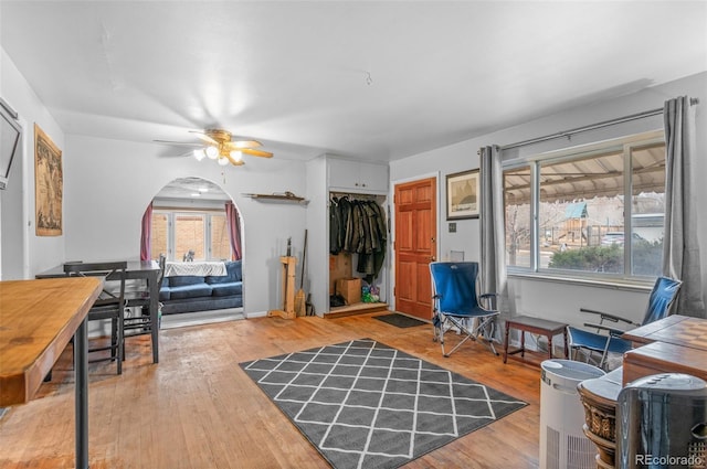 living room featuring arched walkways, a ceiling fan, and wood finished floors