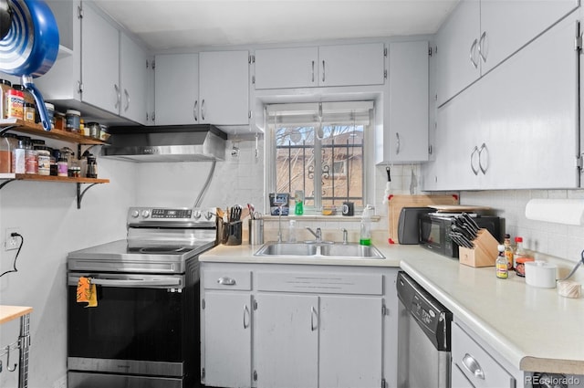 kitchen featuring a sink, decorative backsplash, light countertops, stainless steel appliances, and wall chimney range hood