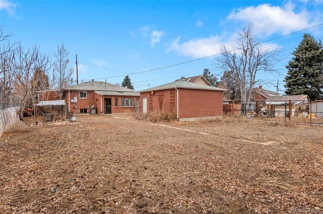 back of house featuring brick siding and fence