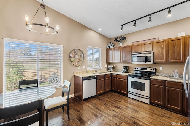 20466 Willowbend Ln, Parker, CO 80138 - kitchen featuring brown cabinetry, appliances with stainless steel finishes, a sink, dark wood-style floors, and a chandelier