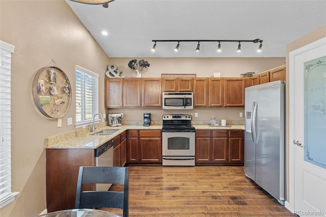 20466 Willowbend Ln, Parker, CO 80138 - kitchen featuring brown cabinetry, wood finished floors, light stone counters, a sink, and stainless steel appliances