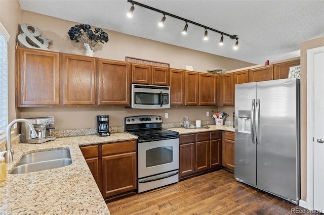20466 Willowbend Ln, Parker, CO 80138 - kitchen featuring appliances with stainless steel finishes, brown cabinetry, a sink, and dark wood finished floors
