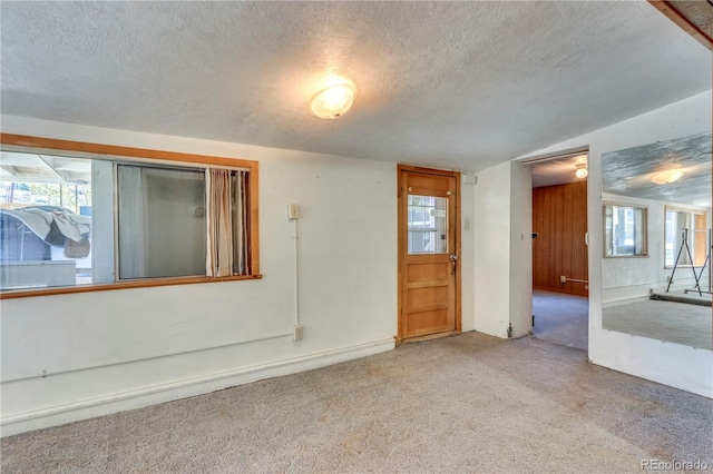 carpeted spare room featuring a textured ceiling and vaulted ceiling