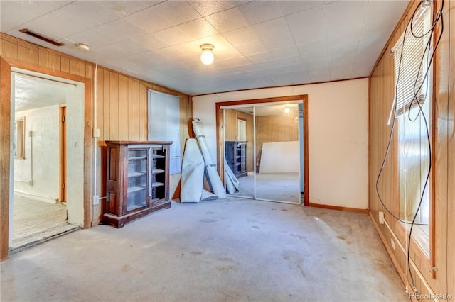 empty room with wooden walls and light colored carpet