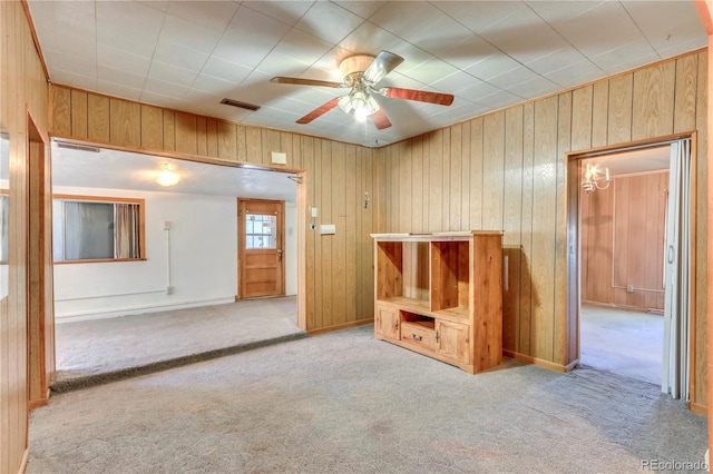 interior space with wood walls, ceiling fan, and light colored carpet