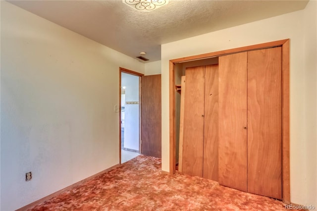 unfurnished bedroom featuring a textured ceiling, light carpet, and a closet