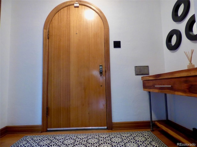foyer entrance featuring baseboards and arched walkways