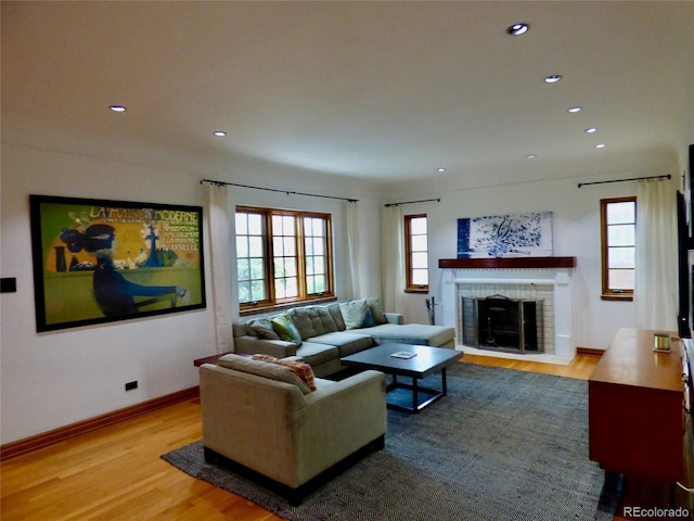 living area featuring recessed lighting, baseboards, a brick fireplace, and wood finished floors