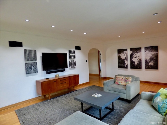 living room featuring recessed lighting, arched walkways, baseboards, and wood finished floors