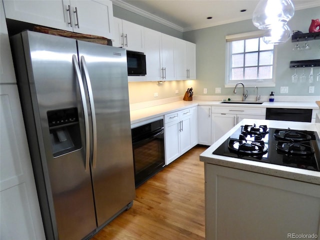 kitchen featuring crown molding, light wood-style floors, white cabinets, a sink, and black appliances