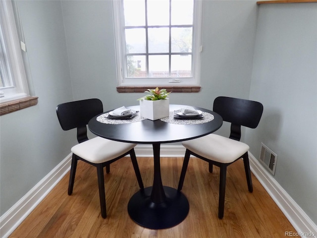 dining room with baseboards, light wood-type flooring, and visible vents