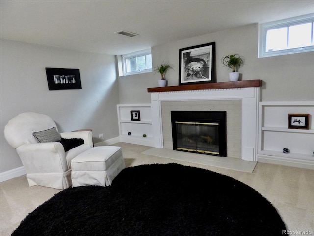 sitting room featuring visible vents, carpet floors, a brick fireplace, baseboards, and built in shelves
