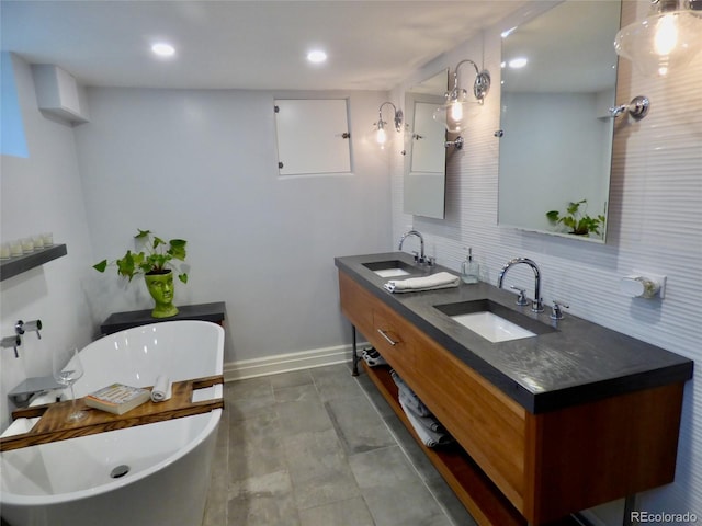 bathroom featuring double vanity, a freestanding tub, decorative backsplash, and a sink