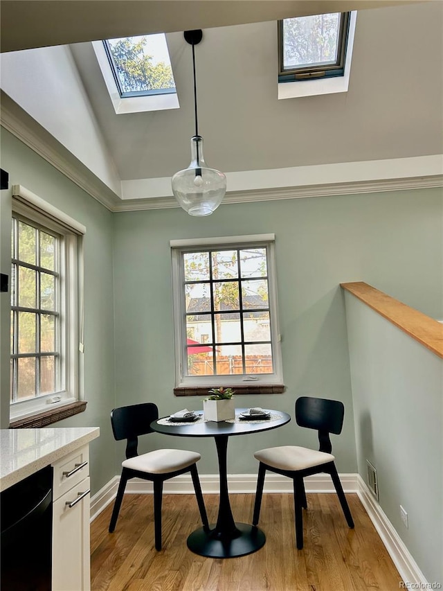 dining space featuring plenty of natural light, light wood-style floors, lofted ceiling with skylight, and visible vents
