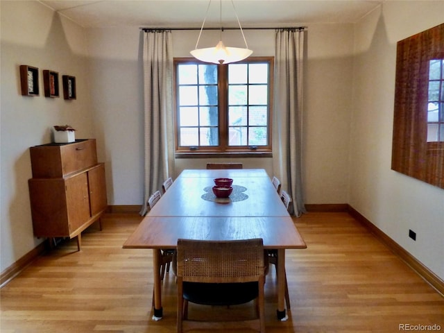dining area with light wood-type flooring and baseboards
