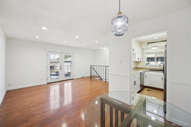 interior space featuring light wood-style flooring, baseboards, a textured ceiling, and recessed lighting