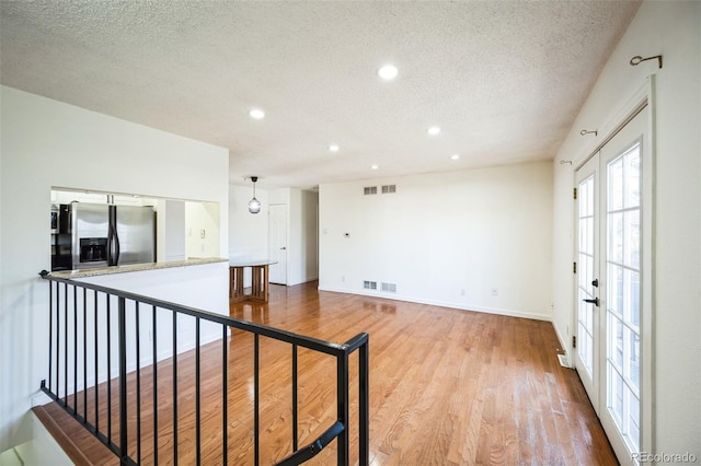 empty room with a textured ceiling, visible vents, and wood finished floors