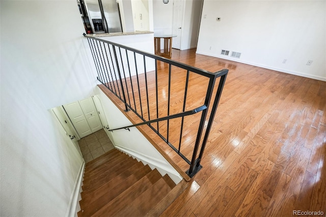 stairs with baseboards, visible vents, and wood finished floors