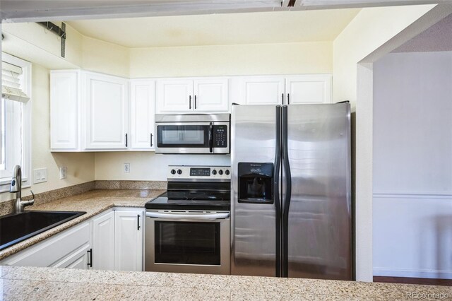 kitchen featuring appliances with stainless steel finishes, a sink, and white cabinetry