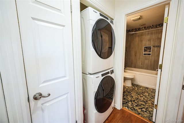 washroom featuring laundry area, wood finished floors, and stacked washer and clothes dryer