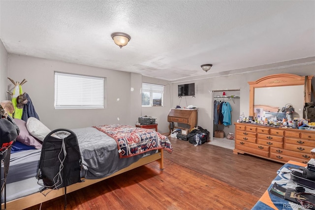 bedroom with a textured ceiling, a closet, and hardwood / wood-style floors