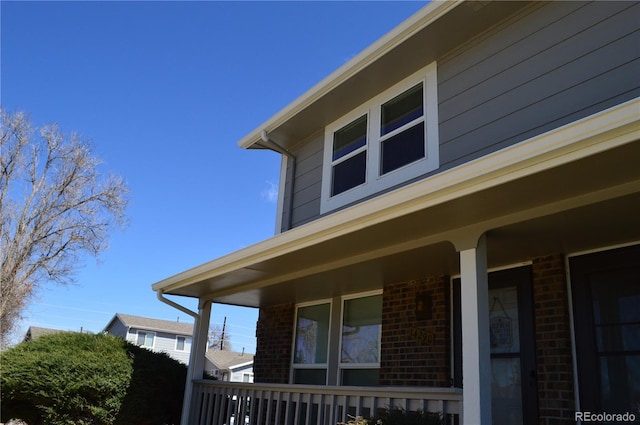 view of side of property with covered porch and brick siding