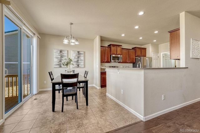 kitchen with pendant lighting, kitchen peninsula, light tile patterned flooring, an inviting chandelier, and stainless steel appliances