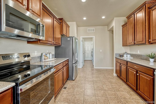 kitchen with light tile patterned floors, light stone counters, washer / dryer, and stainless steel appliances