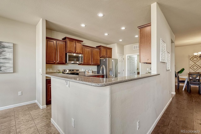 kitchen with a kitchen breakfast bar, kitchen peninsula, stainless steel appliances, and an inviting chandelier