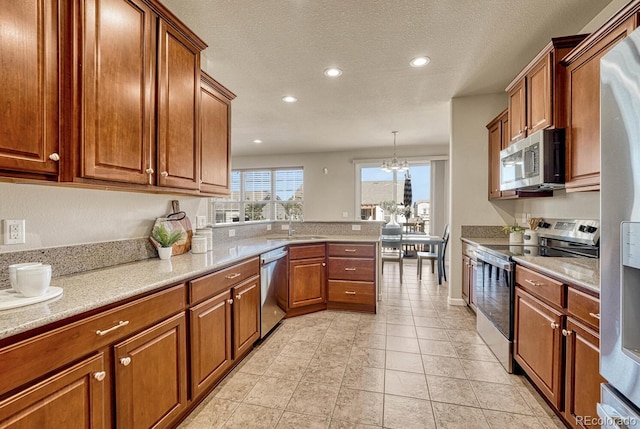 kitchen with stainless steel appliances, sink, hanging light fixtures, a chandelier, and light tile patterned floors