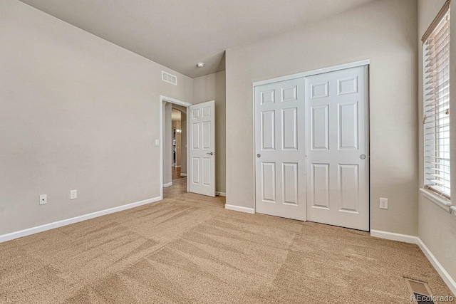 unfurnished bedroom featuring light colored carpet and a closet