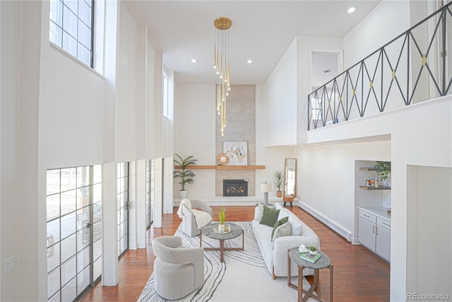 living room with a large fireplace, dark hardwood / wood-style floors, and a towering ceiling