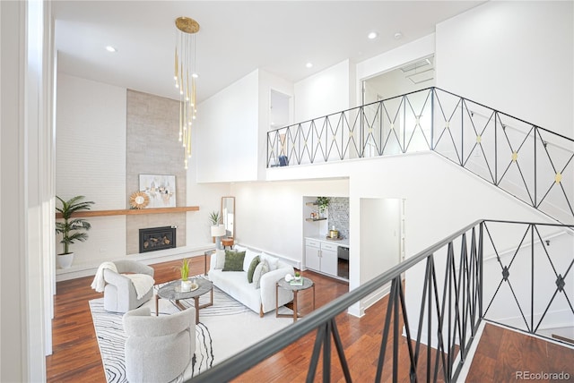 living room with a fireplace, a towering ceiling, and hardwood / wood-style floors