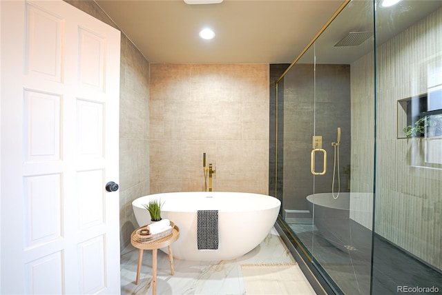 bathroom featuring shower with separate bathtub and tile walls