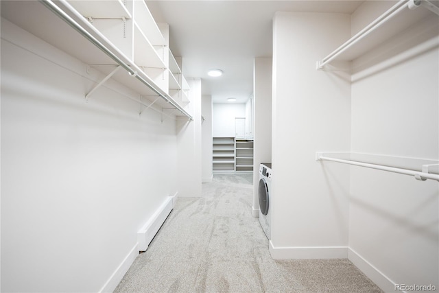 spacious closet with a baseboard heating unit, washer / dryer, and light colored carpet