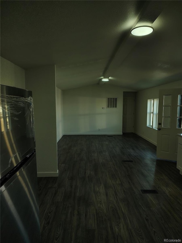 interior space with lofted ceiling, dark wood-style floors, visible vents, and baseboards