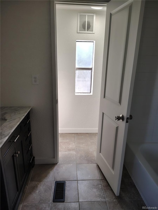 bathroom with a tub, visible vents, and baseboards