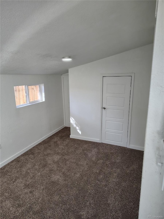 unfurnished room with baseboards, dark colored carpet, and a textured ceiling