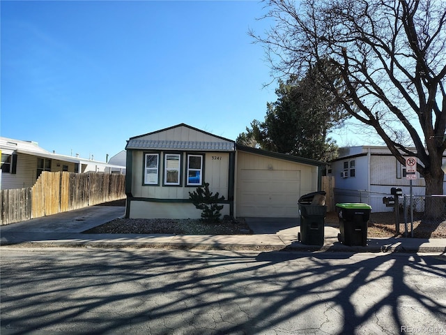 manufactured / mobile home featuring an attached garage, board and batten siding, fence, and concrete driveway