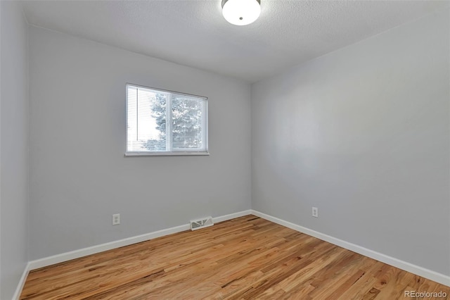 unfurnished room with a textured ceiling and light wood-type flooring