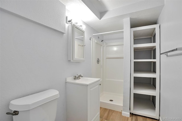 bathroom with vanity, toilet, hardwood / wood-style floors, and a shower