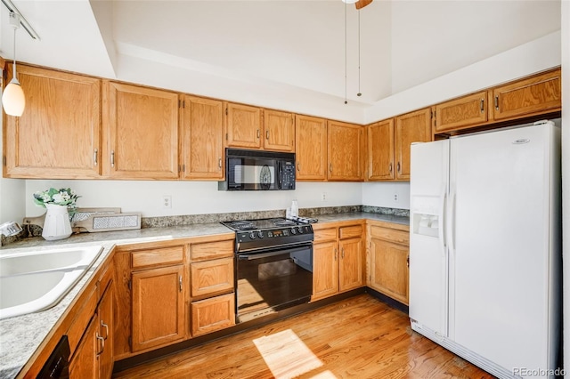 10436 W 84th Pl, Arvada, CO 80005 - kitchen featuring a sink, light wood-style floors, brown cabinetry, black appliances, and hanging light fixtures