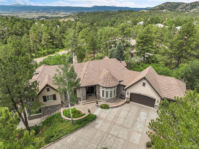 917 Dakota Dr, Castle Rock, CO 80108 - view of front of home featuring stone siding, an attached garage, driveway, a wooded view, and stucco siding