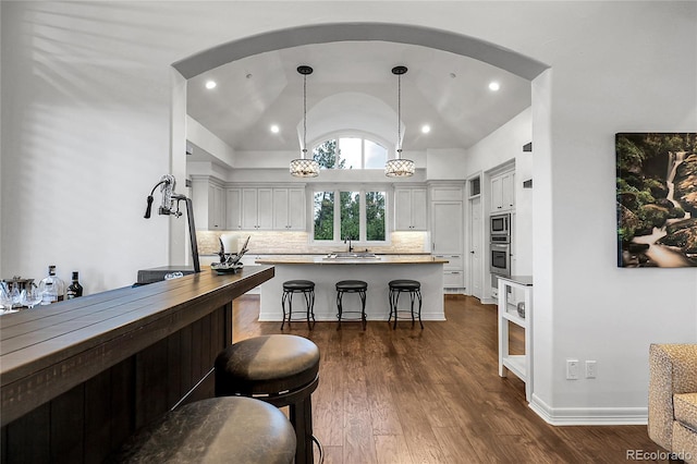 917 Dakota Dr, Castle Rock, CO 80108 - kitchen with stainless steel appliances, lofted ceiling, a kitchen bar, tasteful backsplash, and dark wood-style flooring