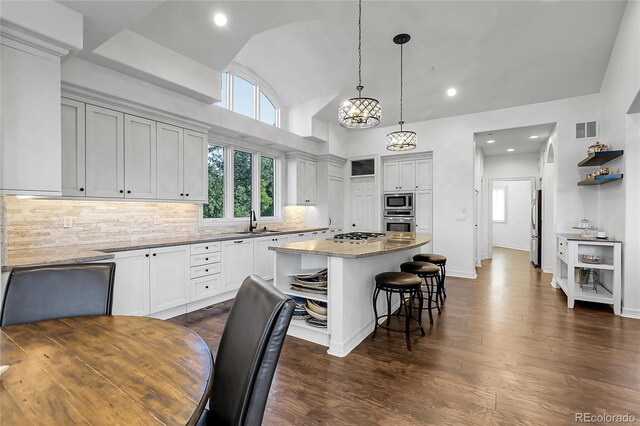 917 Dakota Dr, Castle Rock, CO 80108 - kitchen with appliances with stainless steel finishes, a kitchen breakfast bar, a kitchen island, dark wood-type flooring, and backsplash
