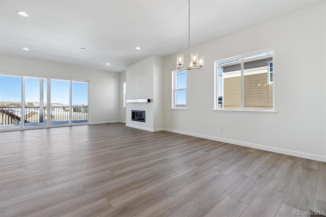 unfurnished living room with a chandelier and light wood-type flooring